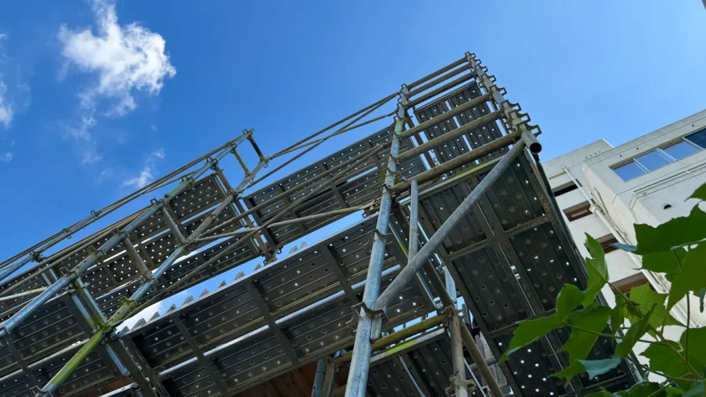 Low-angle view of a facade scaffold showing working platforms, standards, ledgers and diagonal bracing used when preparing scaffold elevation drawings.