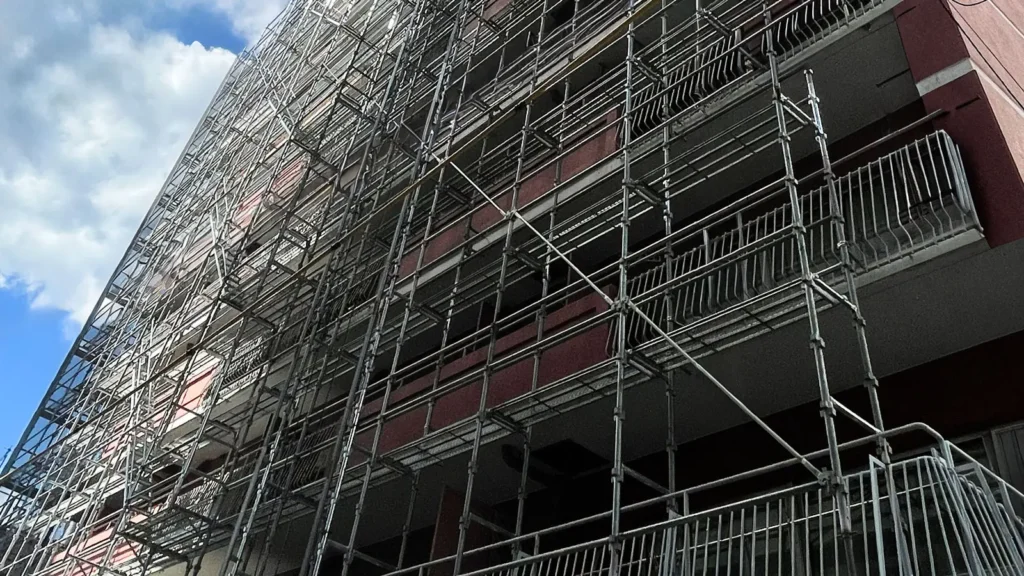 Real multi-storey facade scaffold showing standards, working platforms and bracing around an existing renovation building