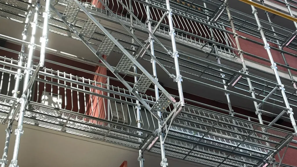 Real scaffold installation showing working platforms, standards, ledgers and diagonal bracing beside a building facade