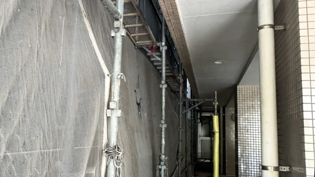Narrow clearance between a scaffold and building, showing standards, platforms and surrounding building elements.