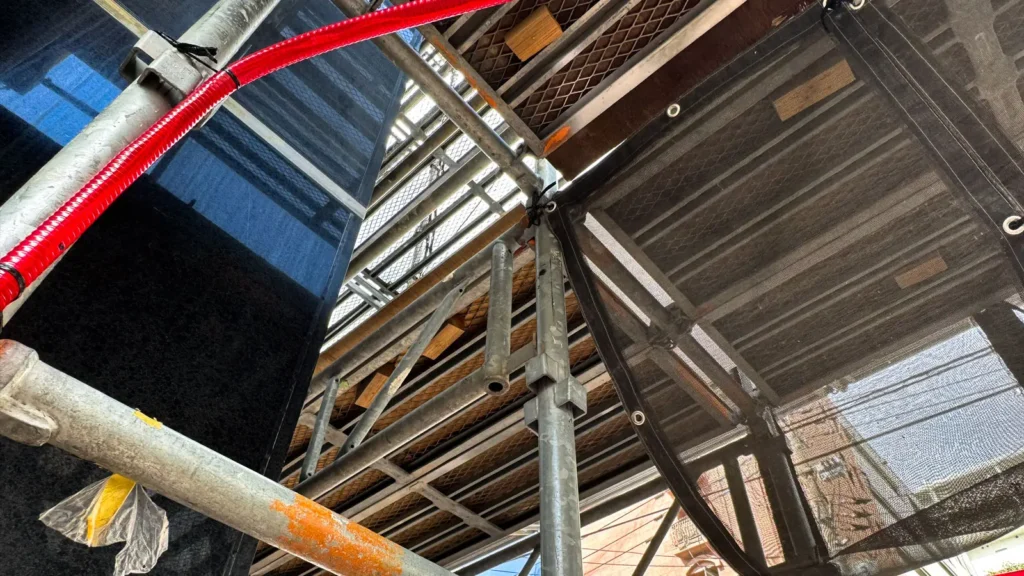 Real-world wedge scaffold viewed from below, showing standards, platforms, horizontal members and mesh sheeting that must be considered in scaffold CAD planning.