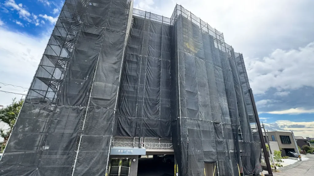 Large building scaffold extensively covered with dark mesh sheeting