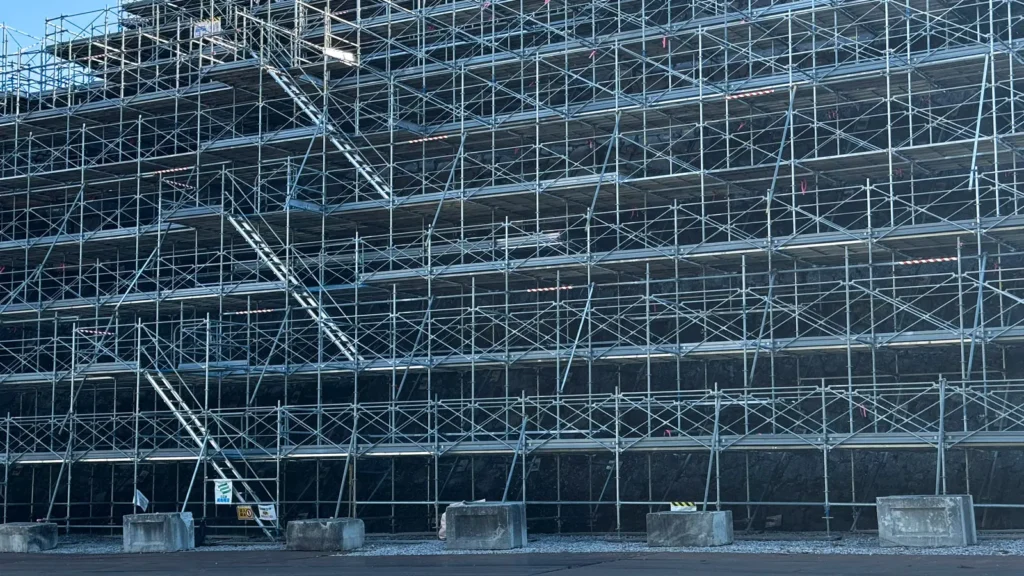 Large multi-level scaffold structure with multiple working platforms and access stairs.