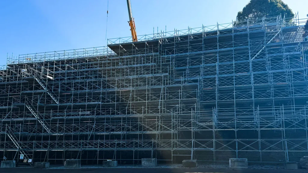 Large multi-level scaffold with repeated bays, changing heights, access stairs and irregular upper-level geometry on a construction project.