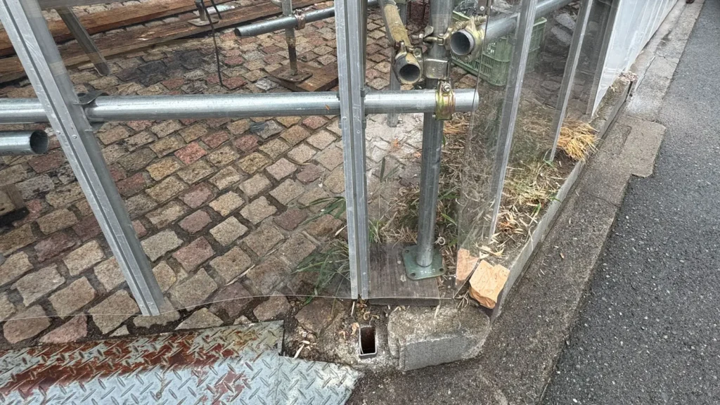 Scaffold base plate supported on a timber sole board beside a curb