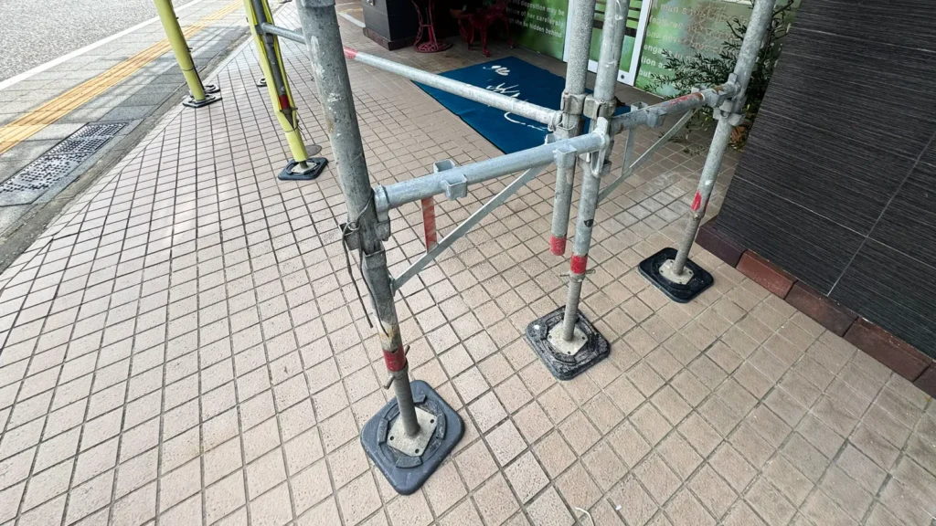 Scaffold base plates supporting standards on a paved surface