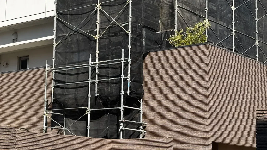 Scaffold with diagonal bracing and mesh sheeting on a building