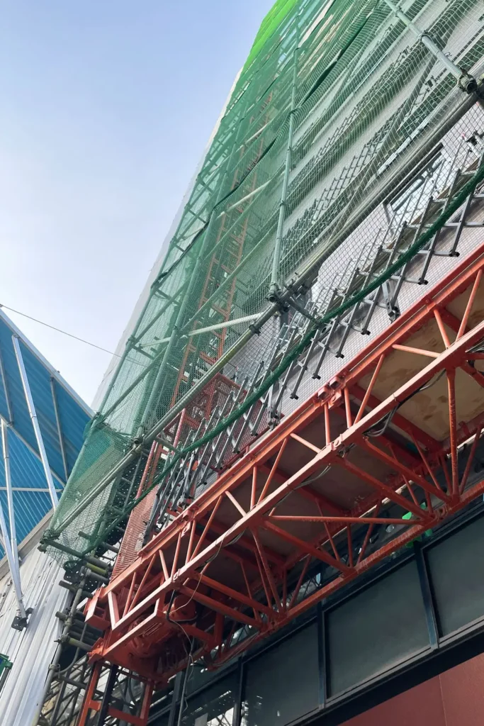 Scaffold supported above an opening by a steel bridge frame
