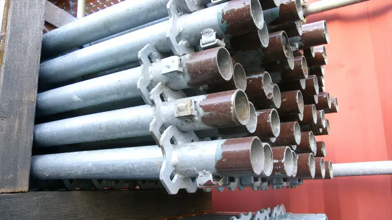 Close-up of stacked scaffold components showing repeated tubular members and connection fittings prepared for construction use.
