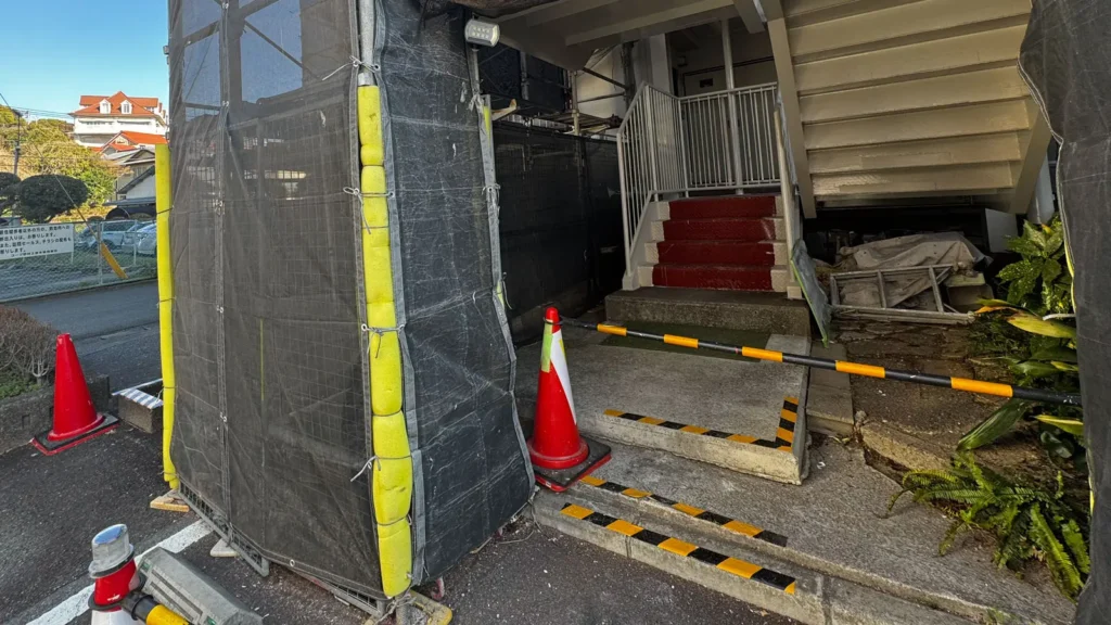 Scaffold beside a building entrance and stairway showing access constraints to review before drawing issue