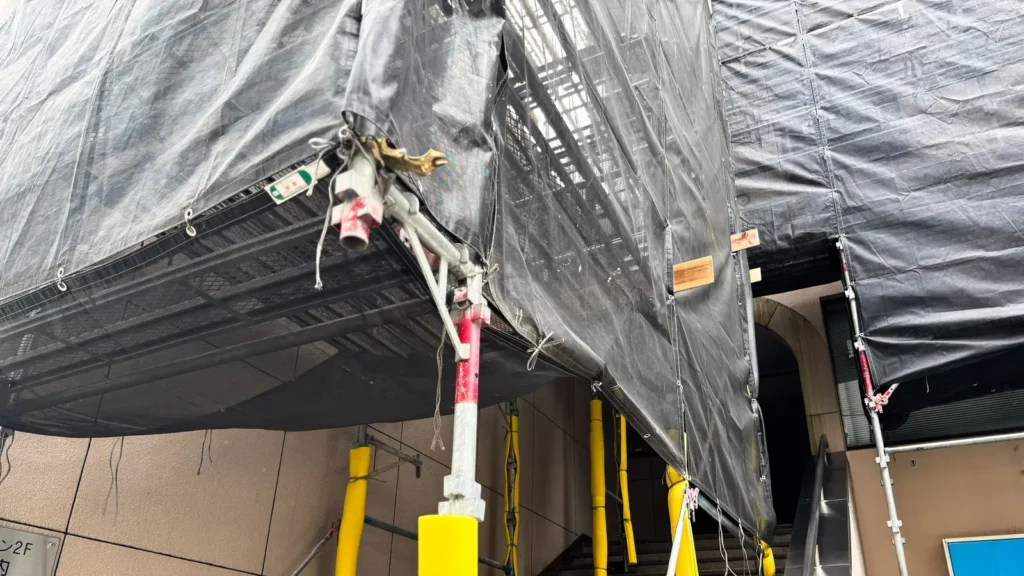Scaffold and protective sheeting installed around a building entrance with existing site constraints.