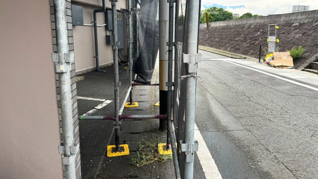 Scaffold erected in a narrow space between a building and road, showing site boundary and clearance constraints