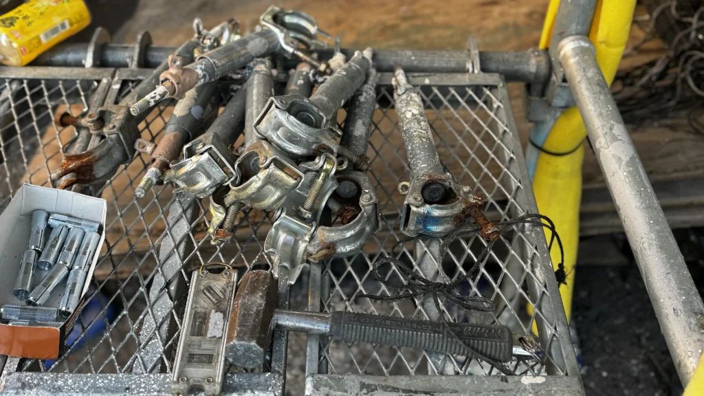 Scaffold components and tools grouped together on a metal working area.