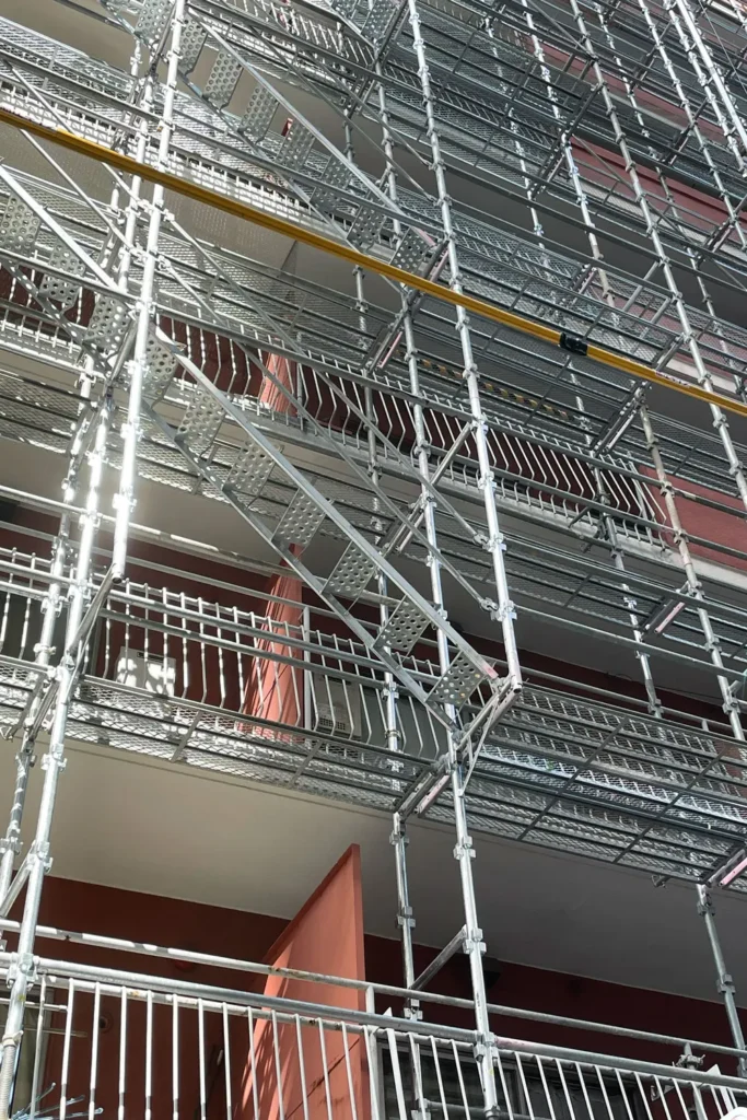 Scaffold platforms arranged around projecting balconies on a multi-storey building