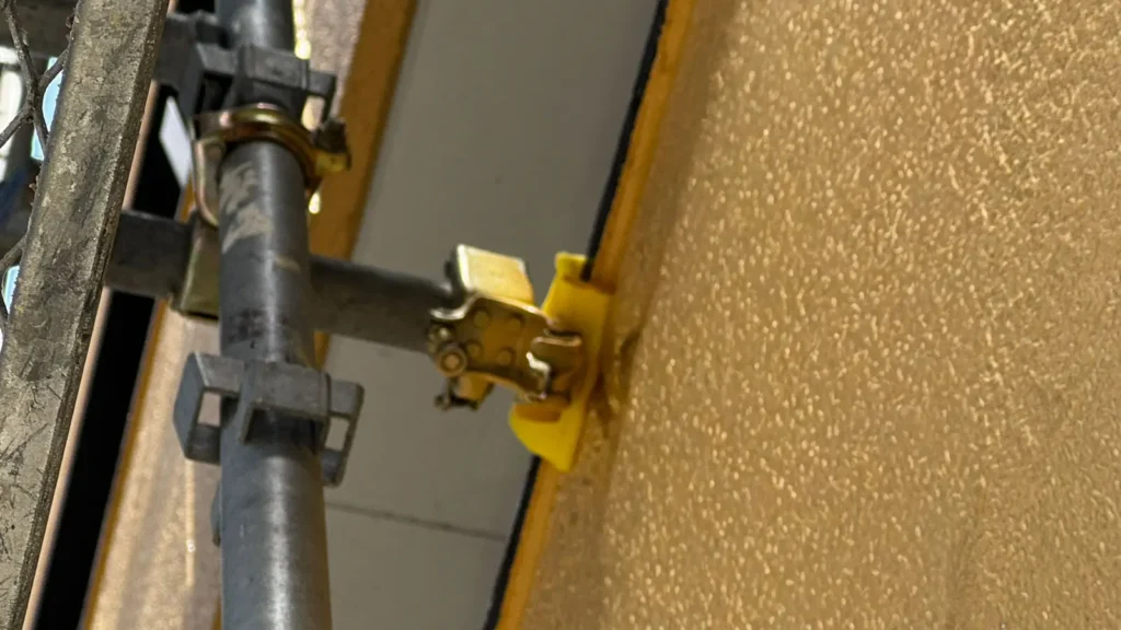 Close-up of a scaffold tie connection, illustrating why the actual fixing point and supporting structure need to be checked when planning tie locations.