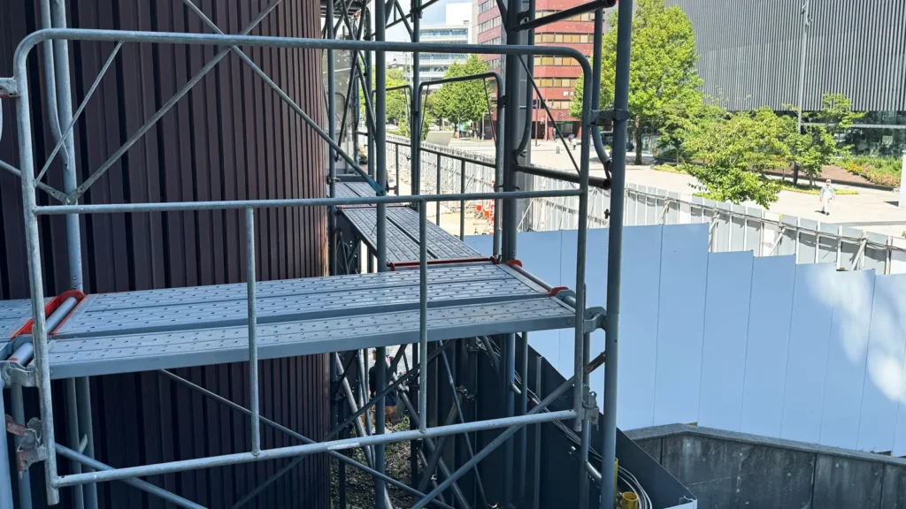 Scaffold working platform layout beside a building façade with metal decks and access space
