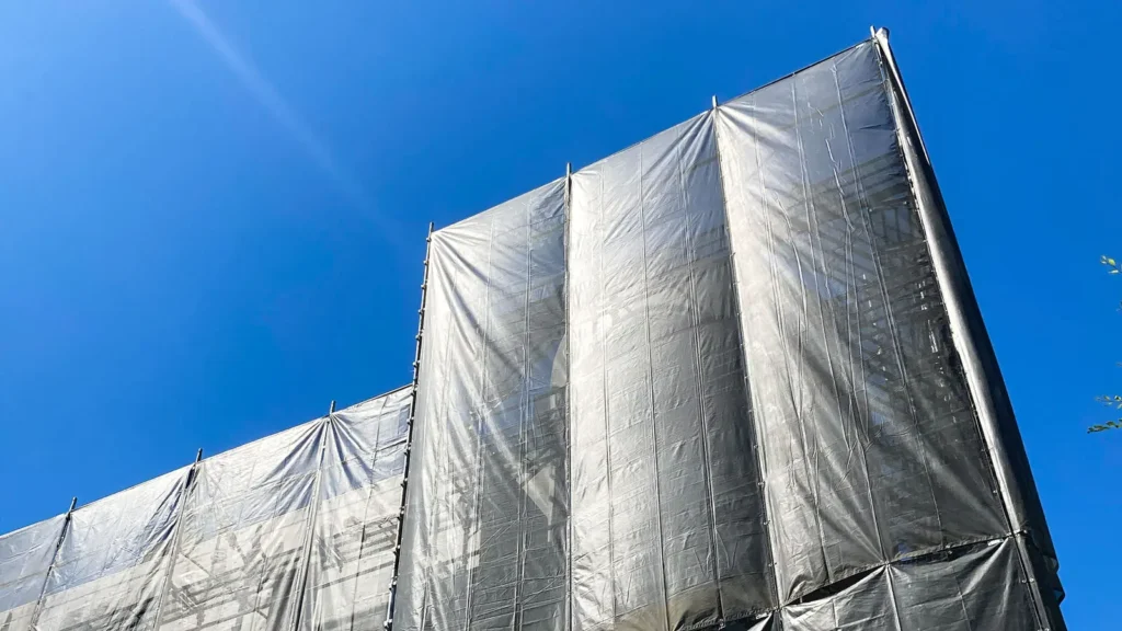 Sheeted scaffold covered with protective sheeting showing a wind-sensitive scaffold condition
